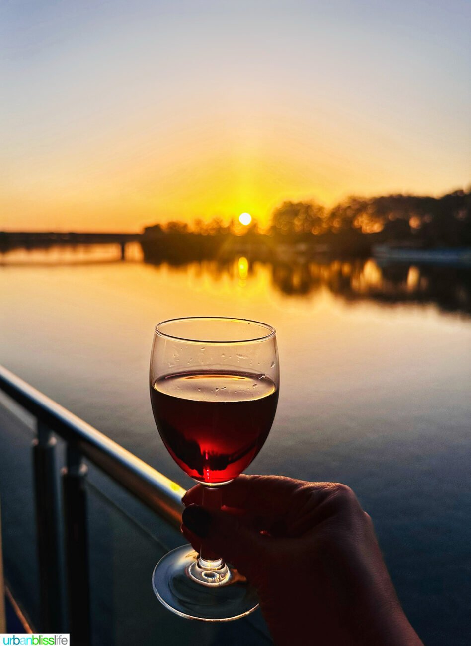 glass of red wine and sunset from a private balcony aboard AmaWaterways AmaKristina river cruise ship.