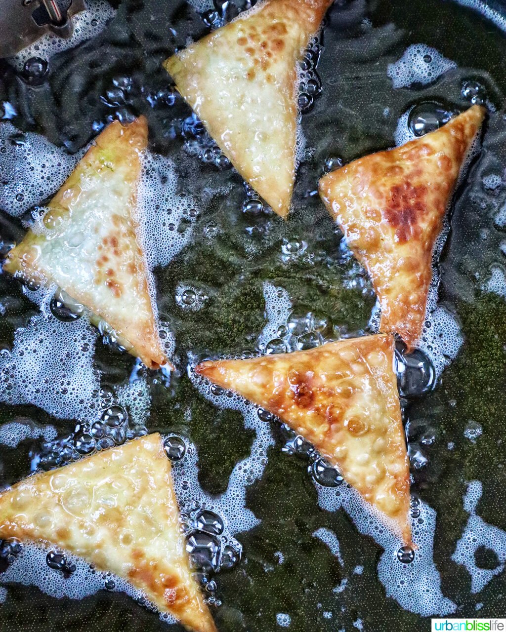 vegan curry samosas frying in a dutch oven.