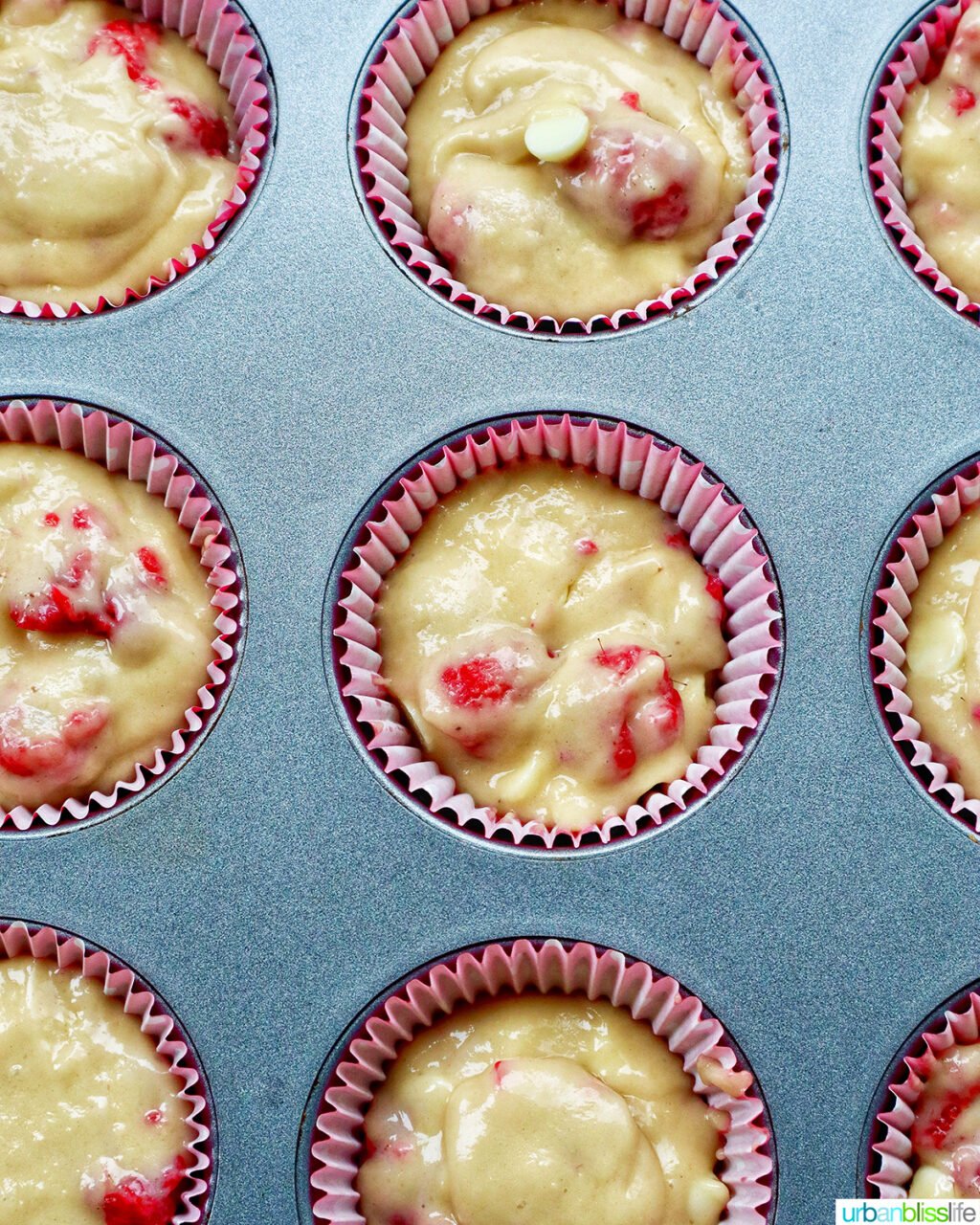 raspberry white chocolate chip muffins in a muffin pan.