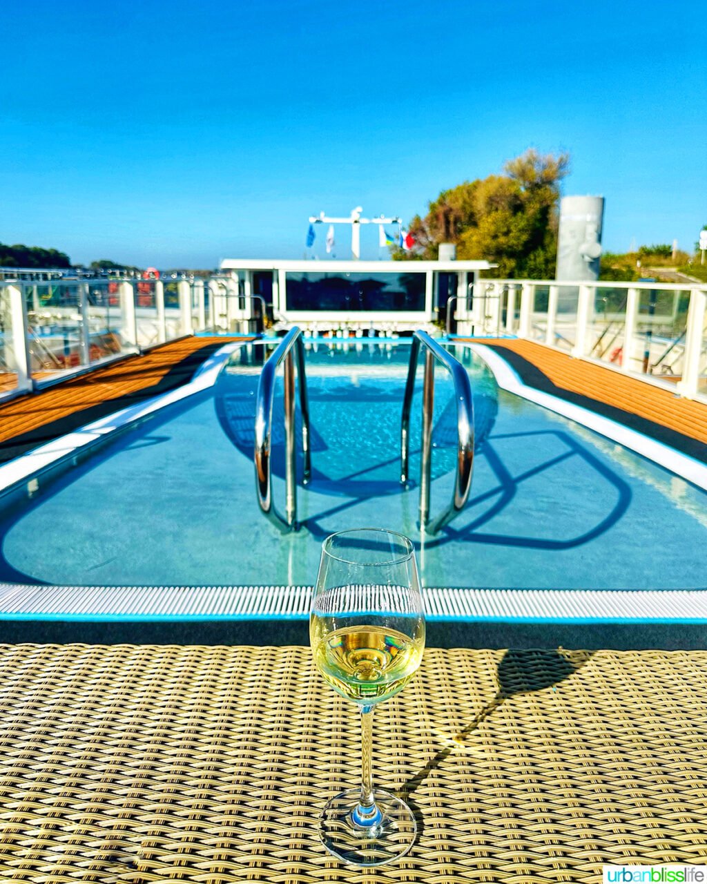 glass of white wine in front of pool aboard AmaWaterways AmaKristina river cruise ship.