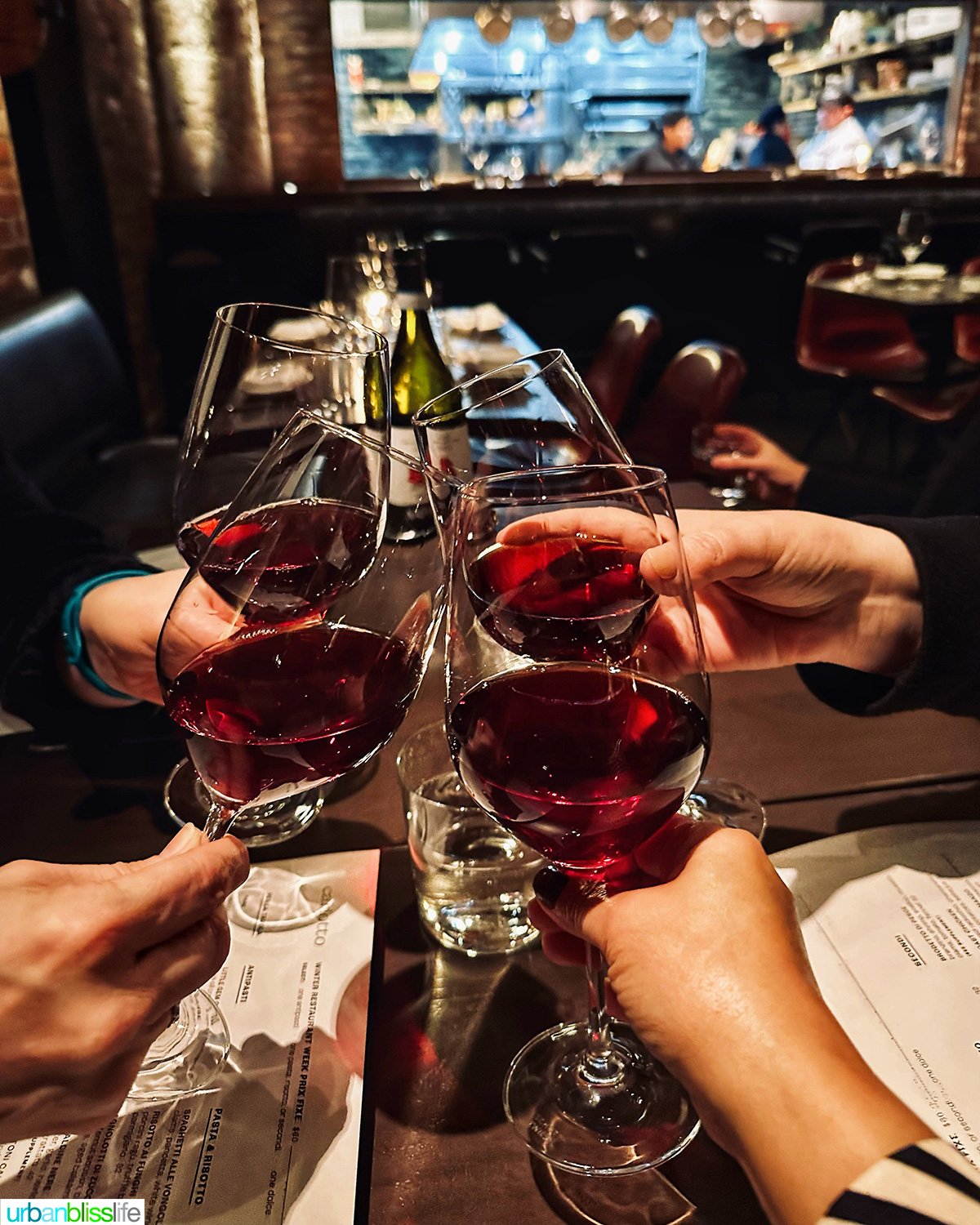 four friends cheers with glasses of red wine.
