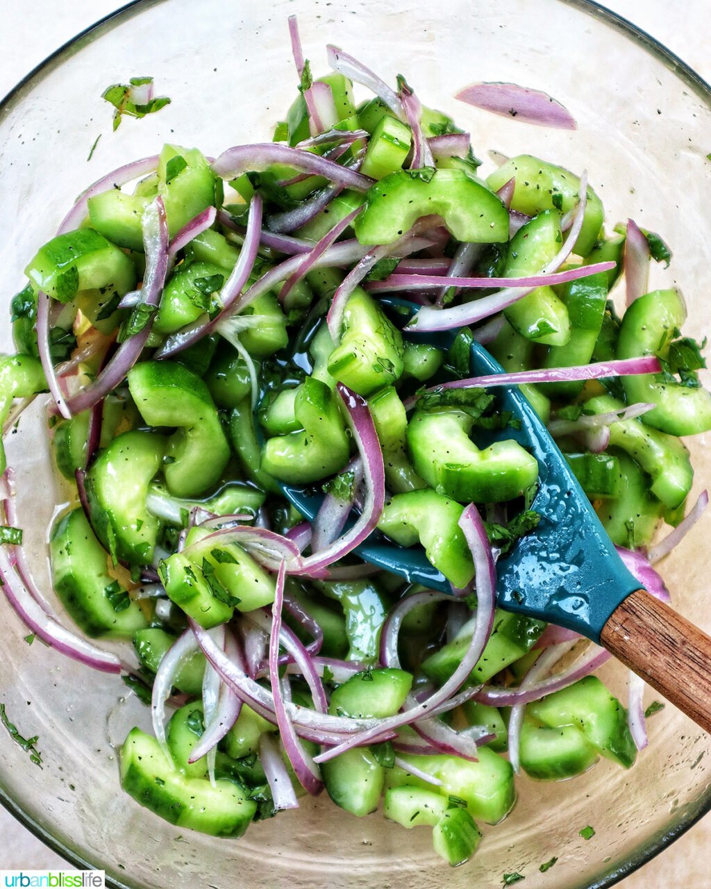 cucumber mint salad in a bowl with wooden spoon.