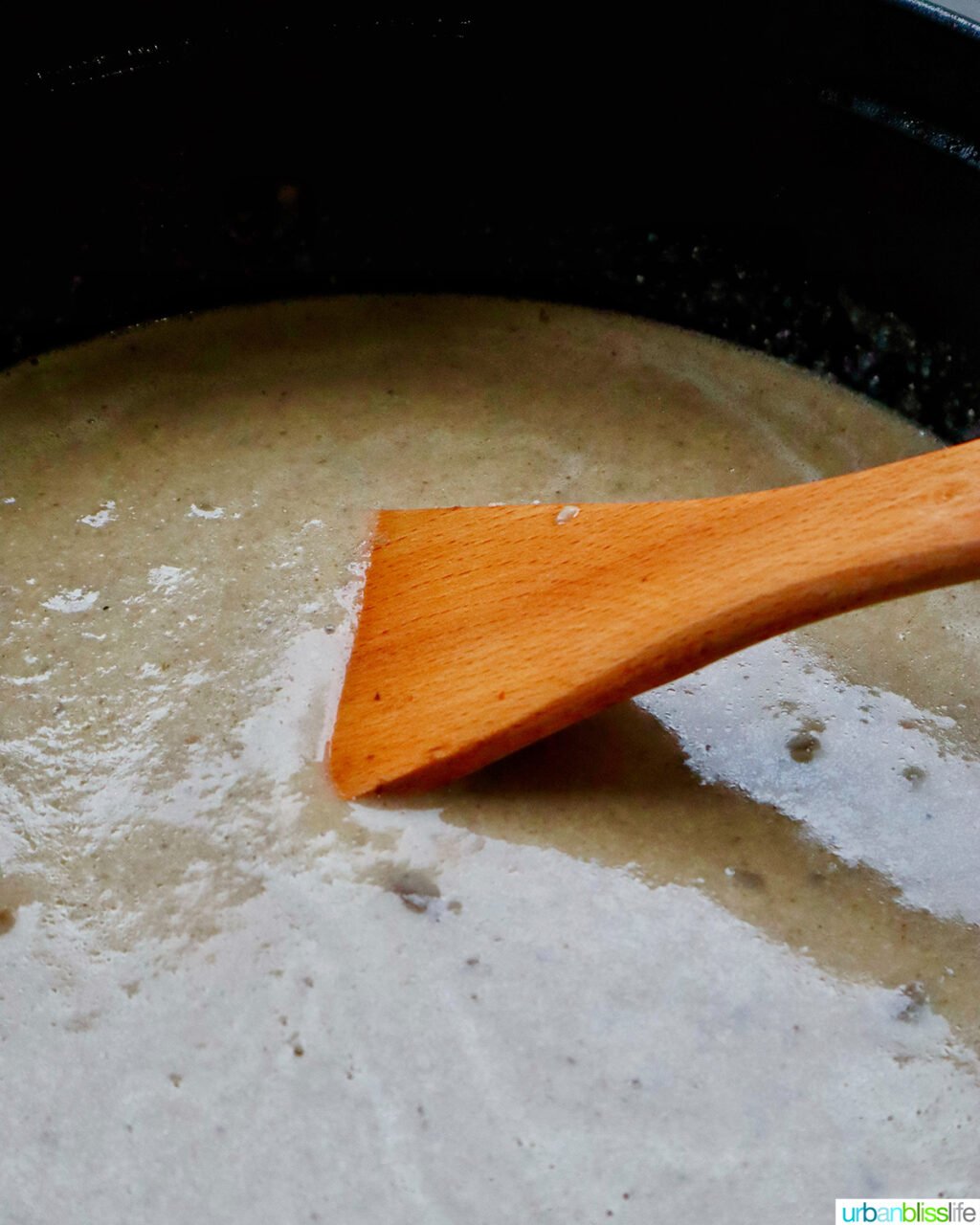 wooden spoon stirring mushroom soup.