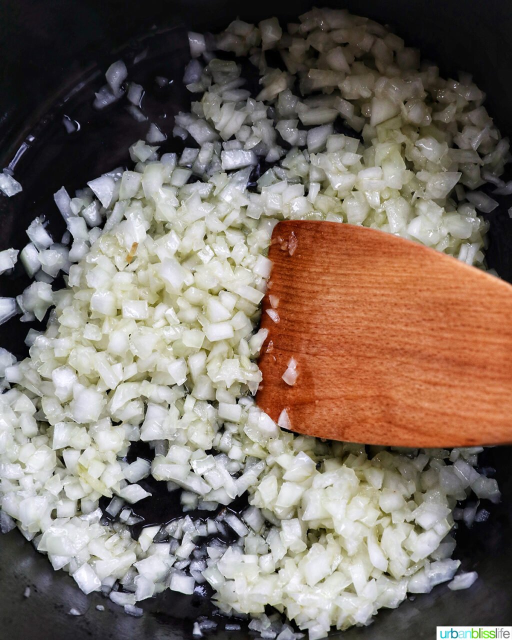 diced onions and wooden spoon in a dutch oven.