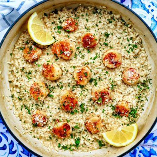 braising pan with scallop risotto with lemon wedge and parsley garnish.