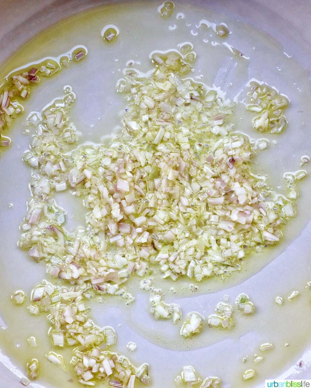 shallots and onions cooking in olive oil in a pan.