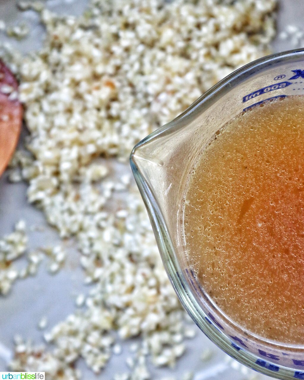 cup of stock over rice in a pan to make scallop risotto.