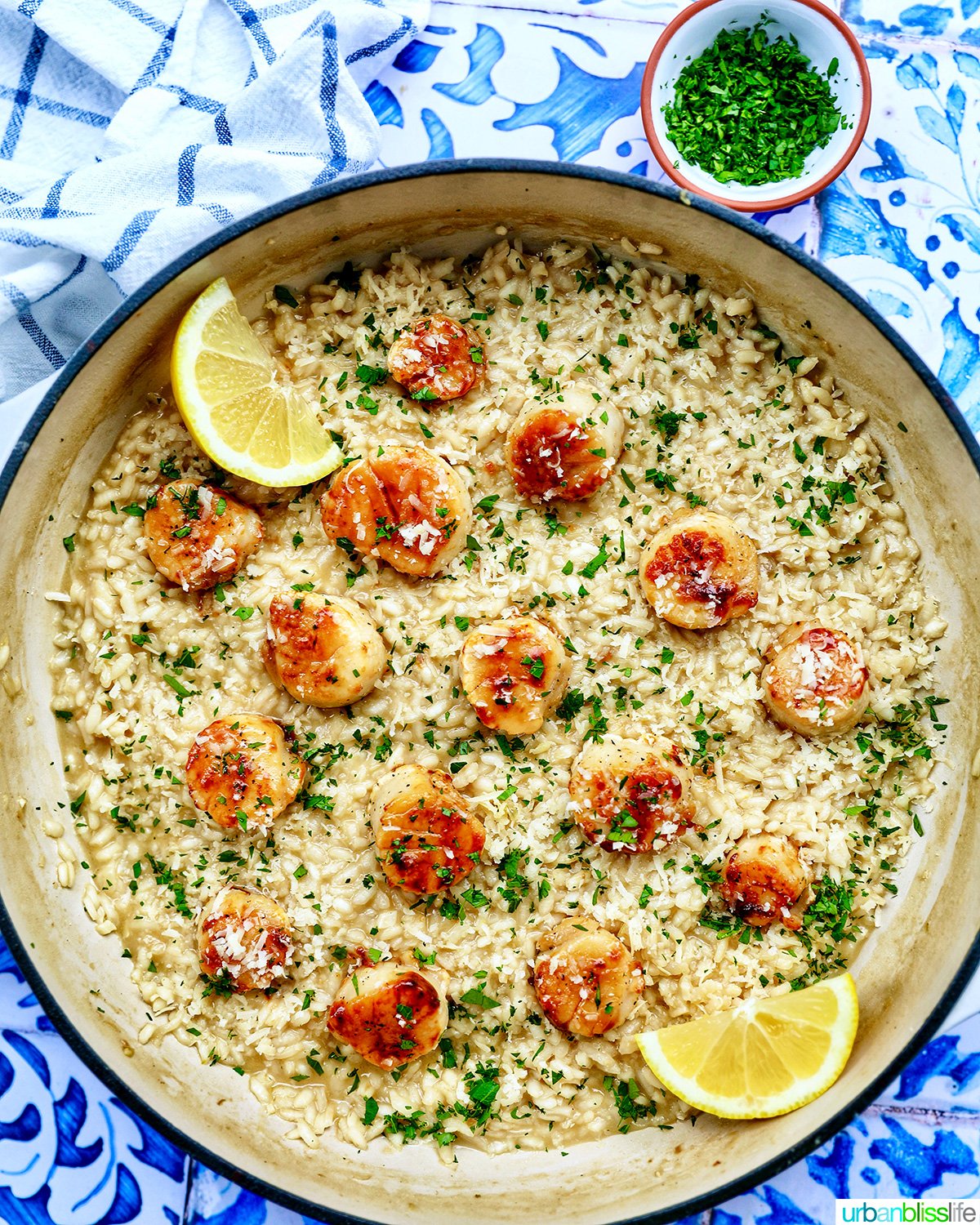 braising pan with scallop risotto with lemon wedge and parsley garnish.