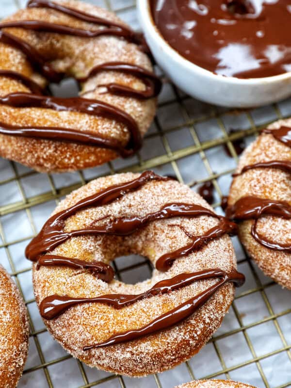 churro donuts on a cooling rack with chocolate drizzle.