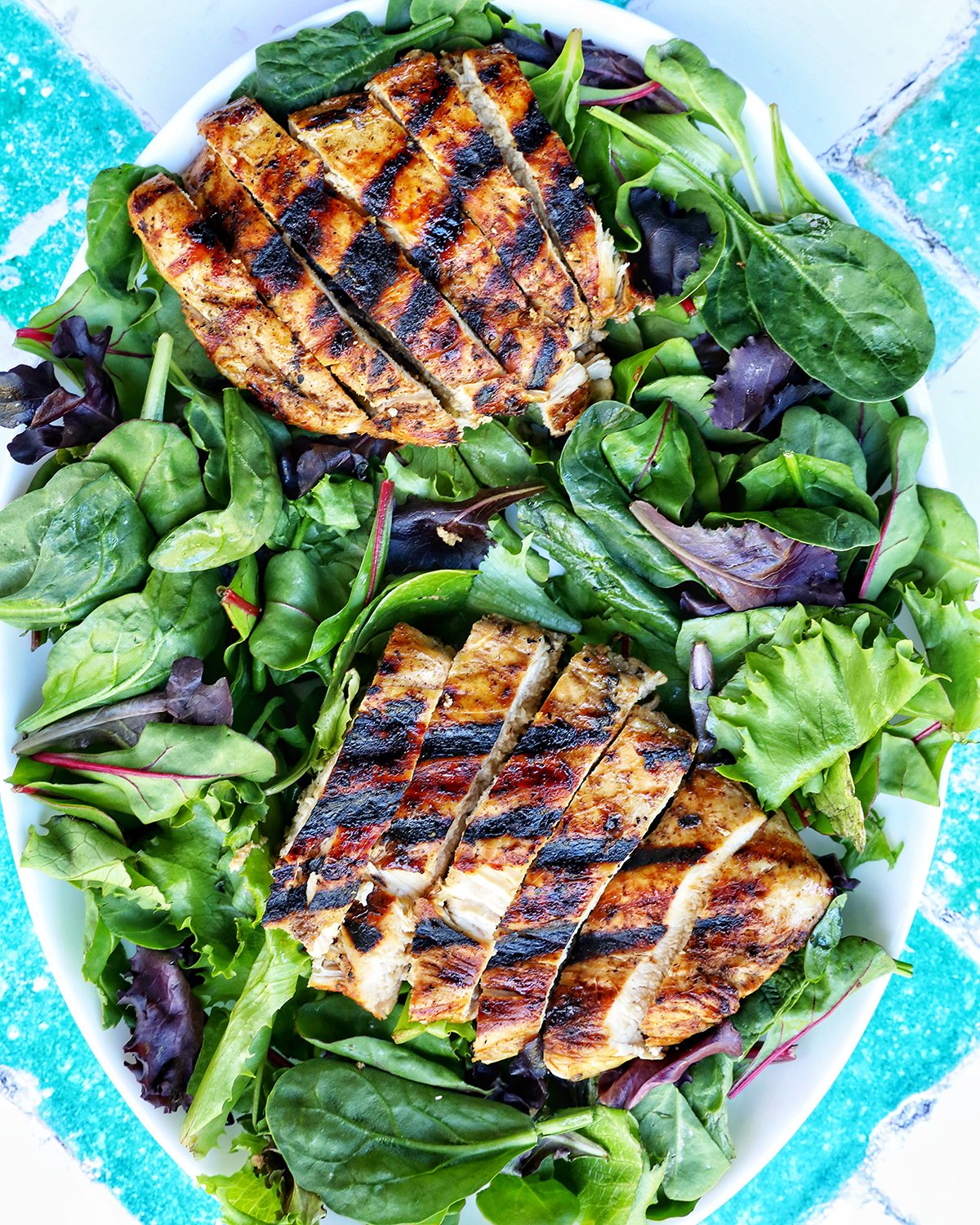 sliced grilled chicken on a bed of mixed greens.