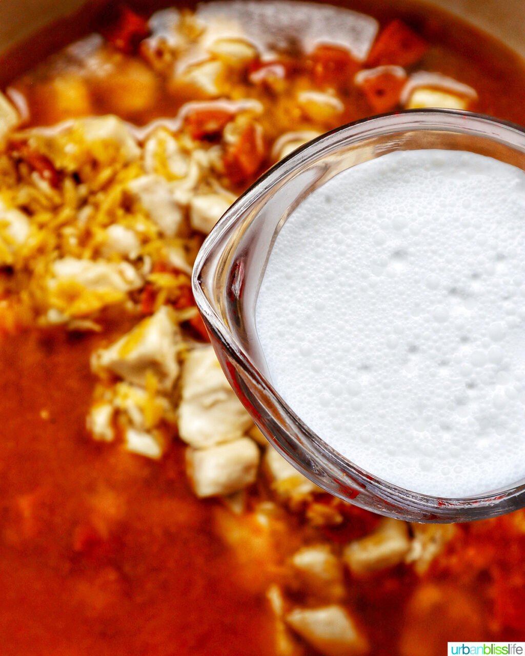 adding cream to chorizo chicken cooking in a pan.