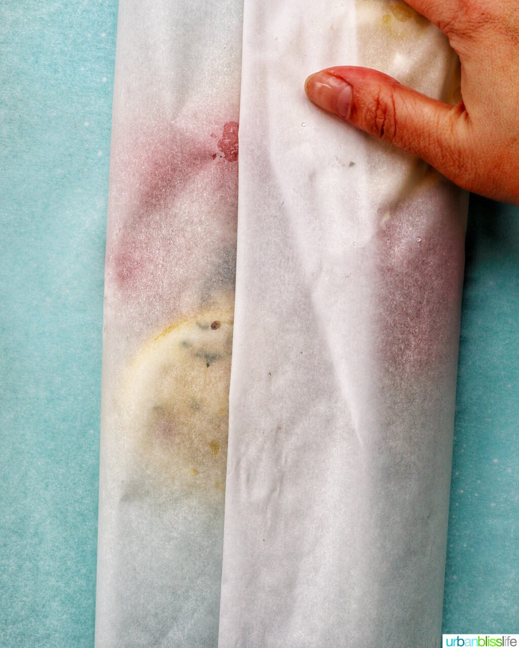 hand wrapping parchment paper around Cod en Papillote.
