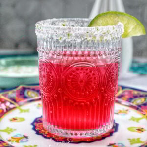 glass of prickly pear margarita with lime slice garnish.