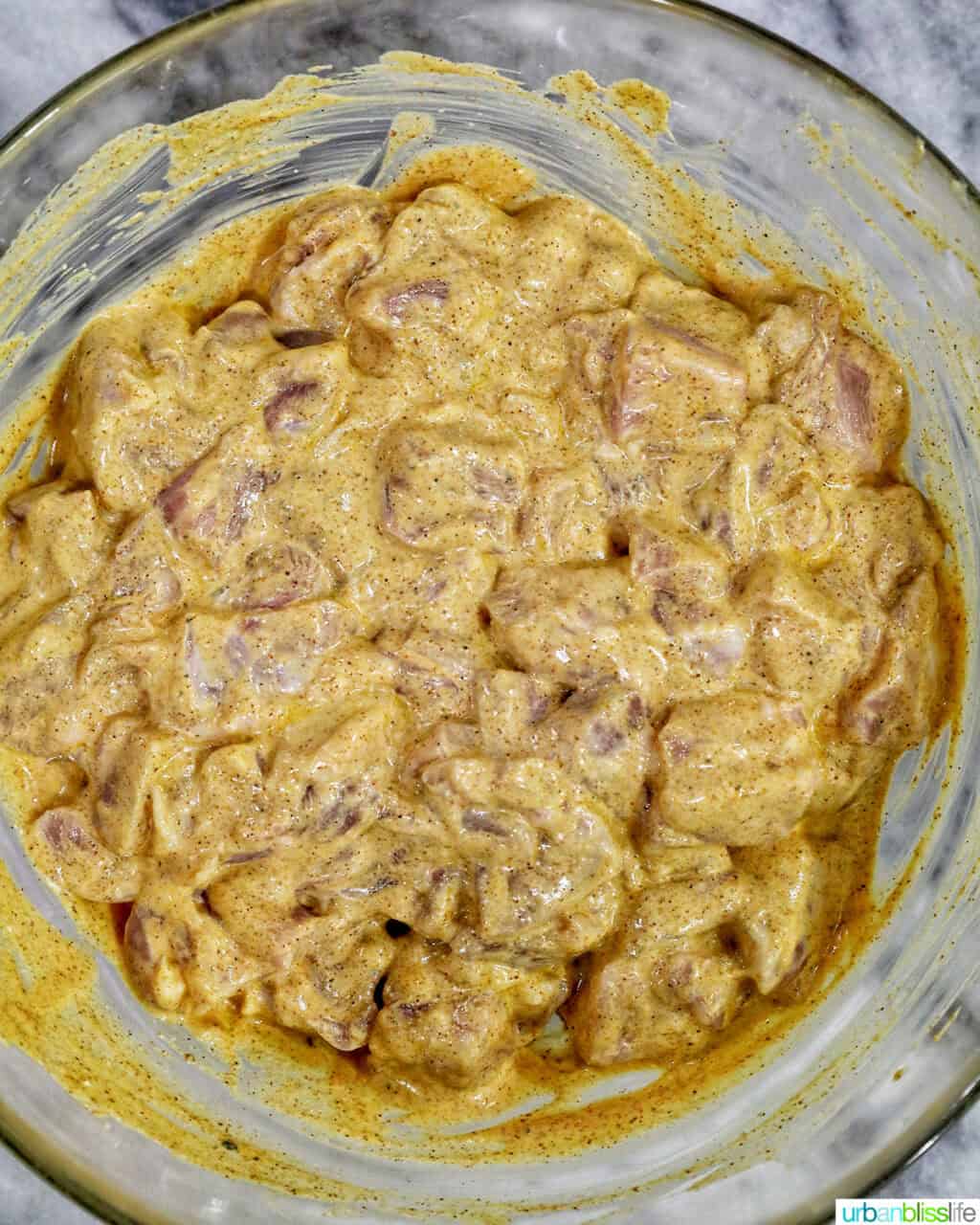 chicken marinating in sauce in a glass bowl.