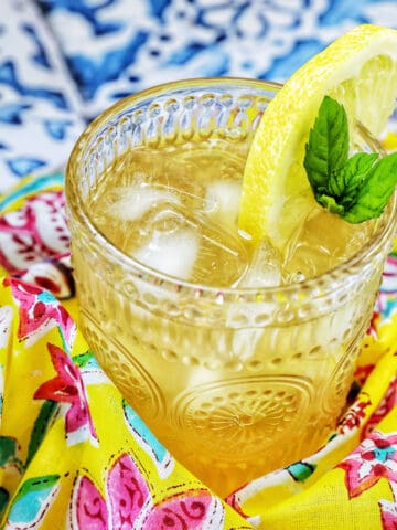 glass of bourbon lemonade on a bright colorful napkin with title text overlay.