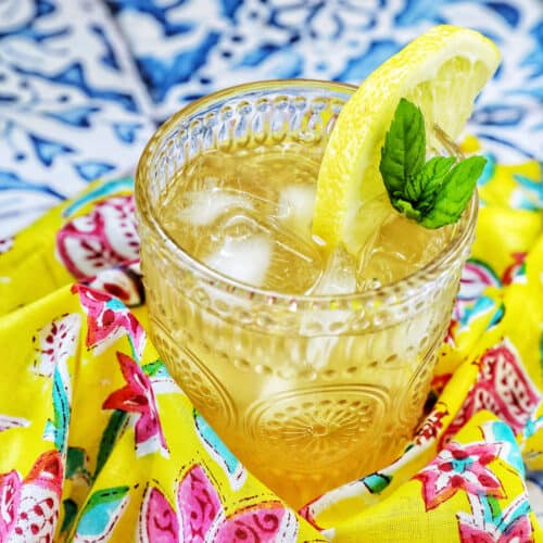 glass of bourbon lemonade on a bright colorful napkin with title text overlay.