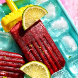 cherry popsicles on ice with slices of lime.