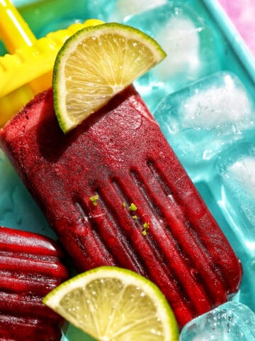 cherry popsicles on ice with slices of lime.