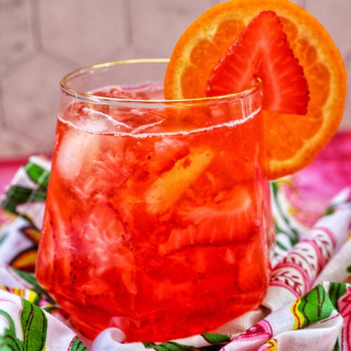 strawberry spritz with orange and strawberry garnish.