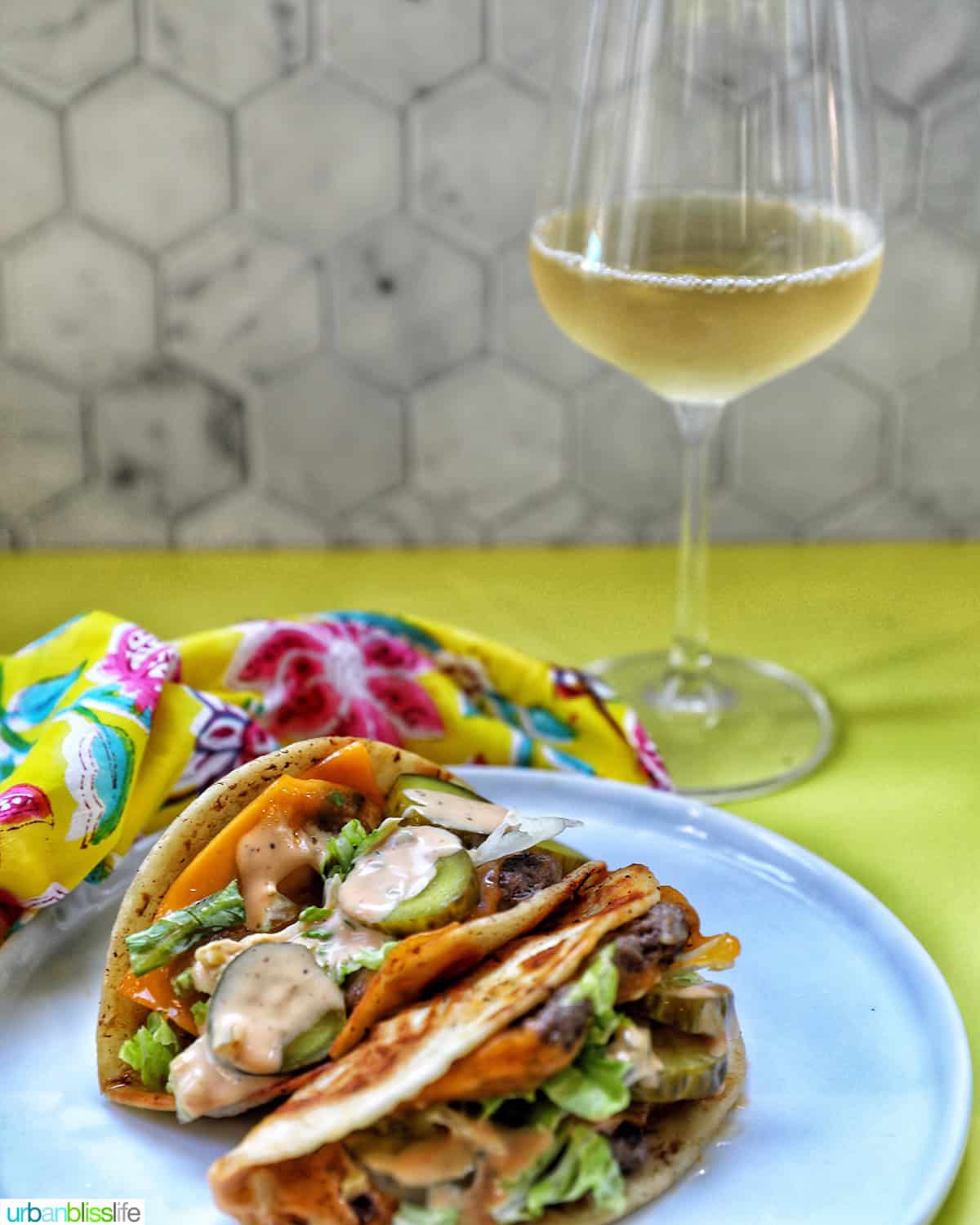 big mac smash tacos on a plate with a glass of wine.
