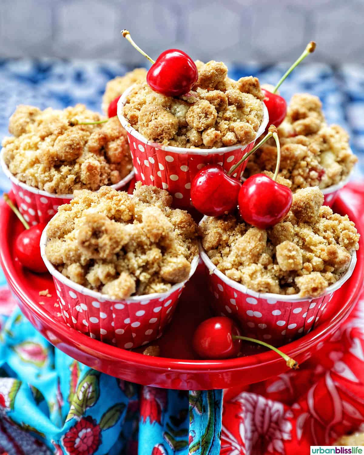stack of cherry muffins with fresh cherries on a red cake stand.