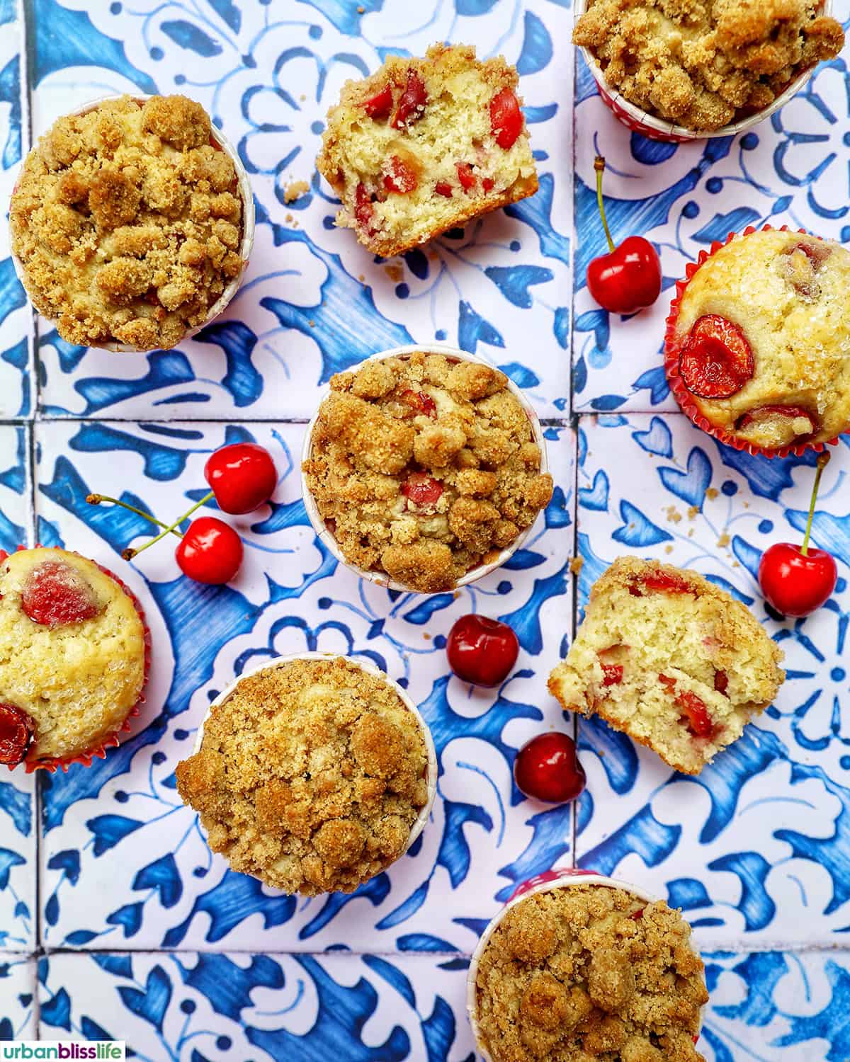 stack of cherry muffins with fresh cherries on a blue and white table.