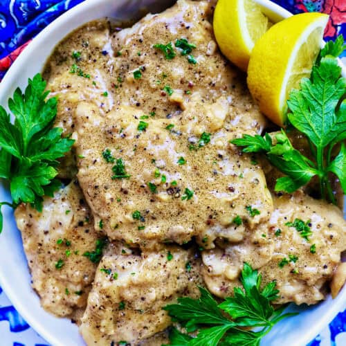 chicken au poivre with herb and lemon slices as garnish.