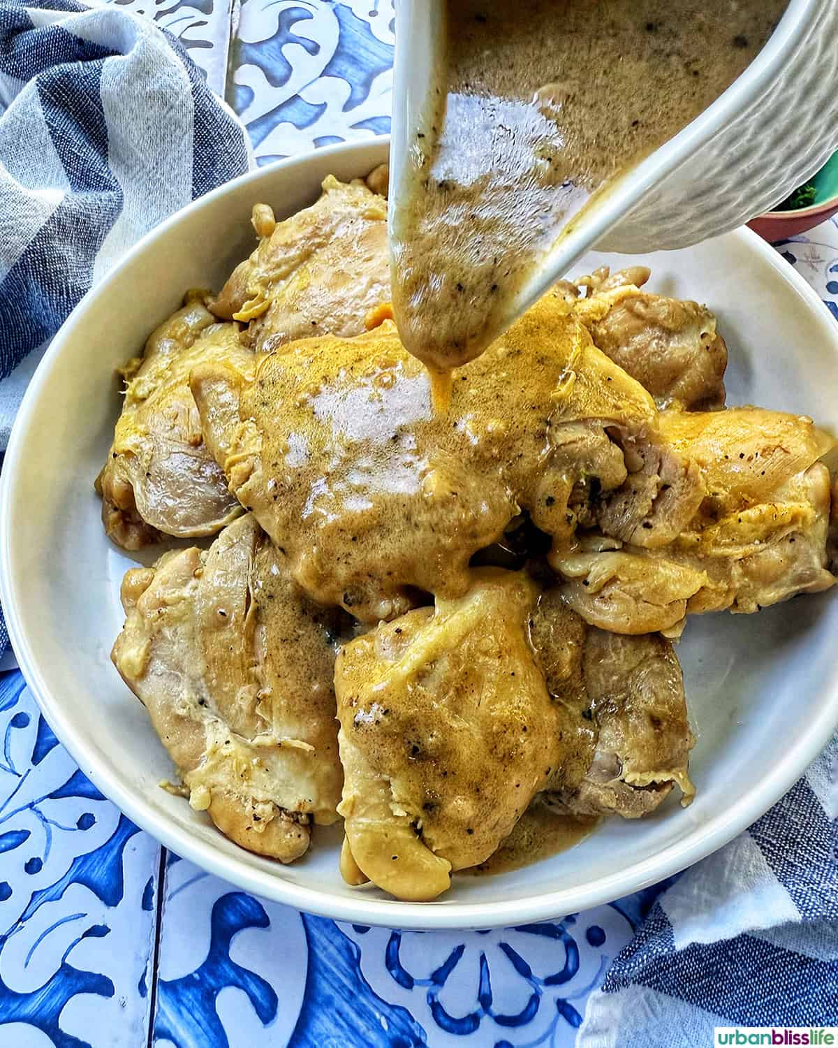 pouring peppercorn sauce over the chicken au poivre.
