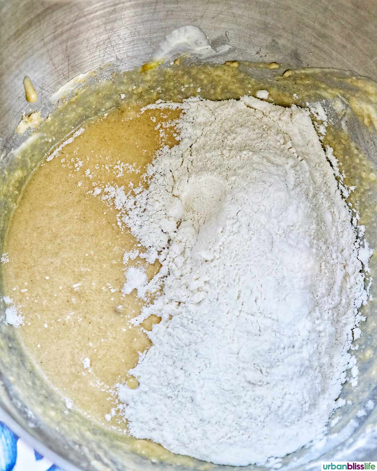 dry ingredients added to wet ingredients in a stainless steel mixing bowl.