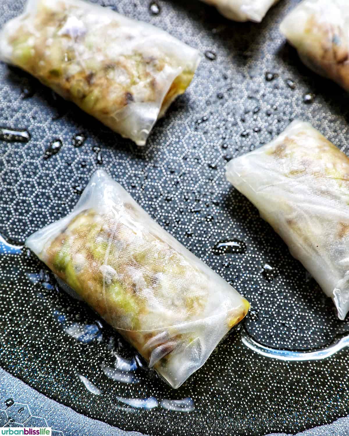 Filled and folded rice paper dumplings in a pan.