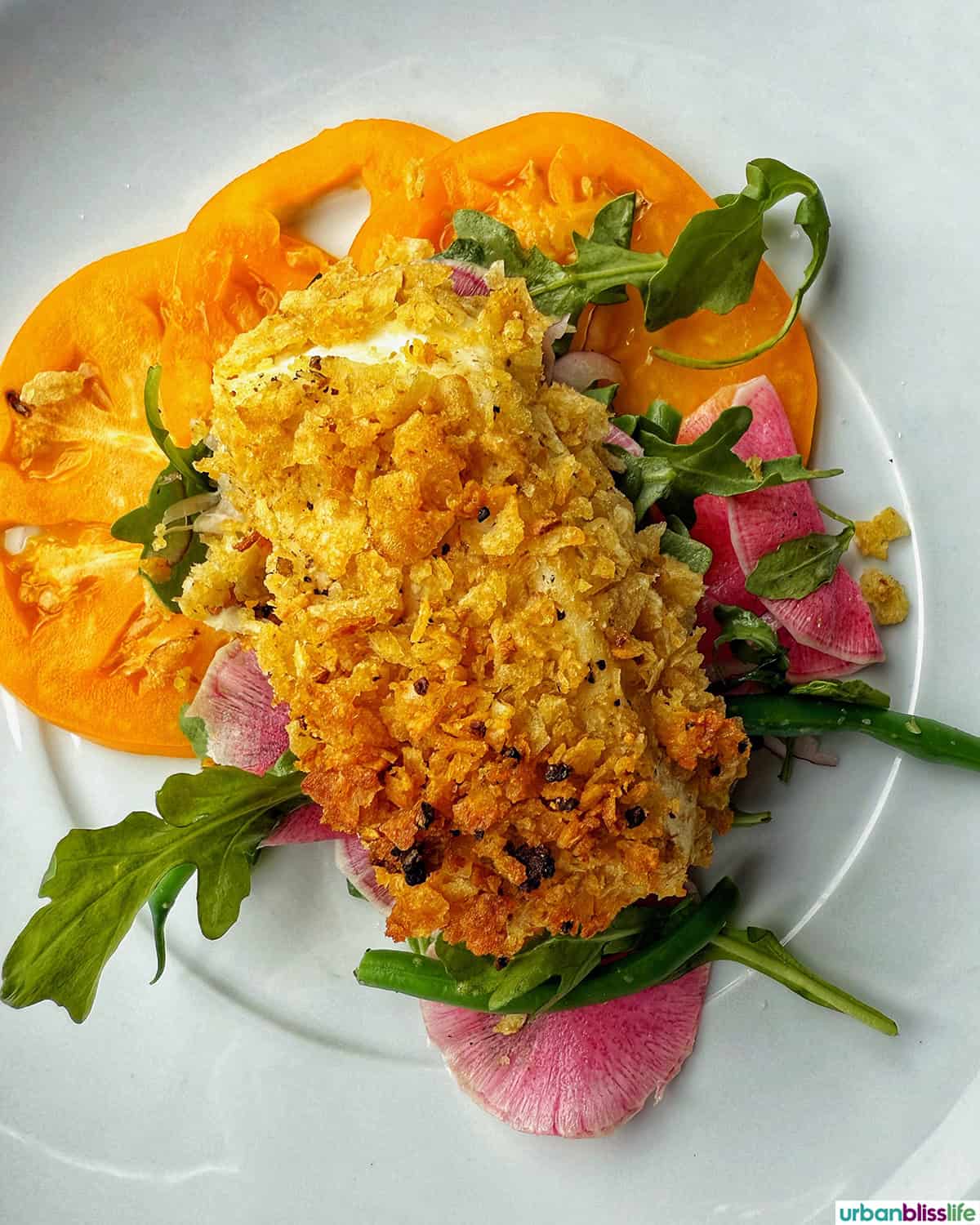 potato chip crusted fish on a plate with veggies.