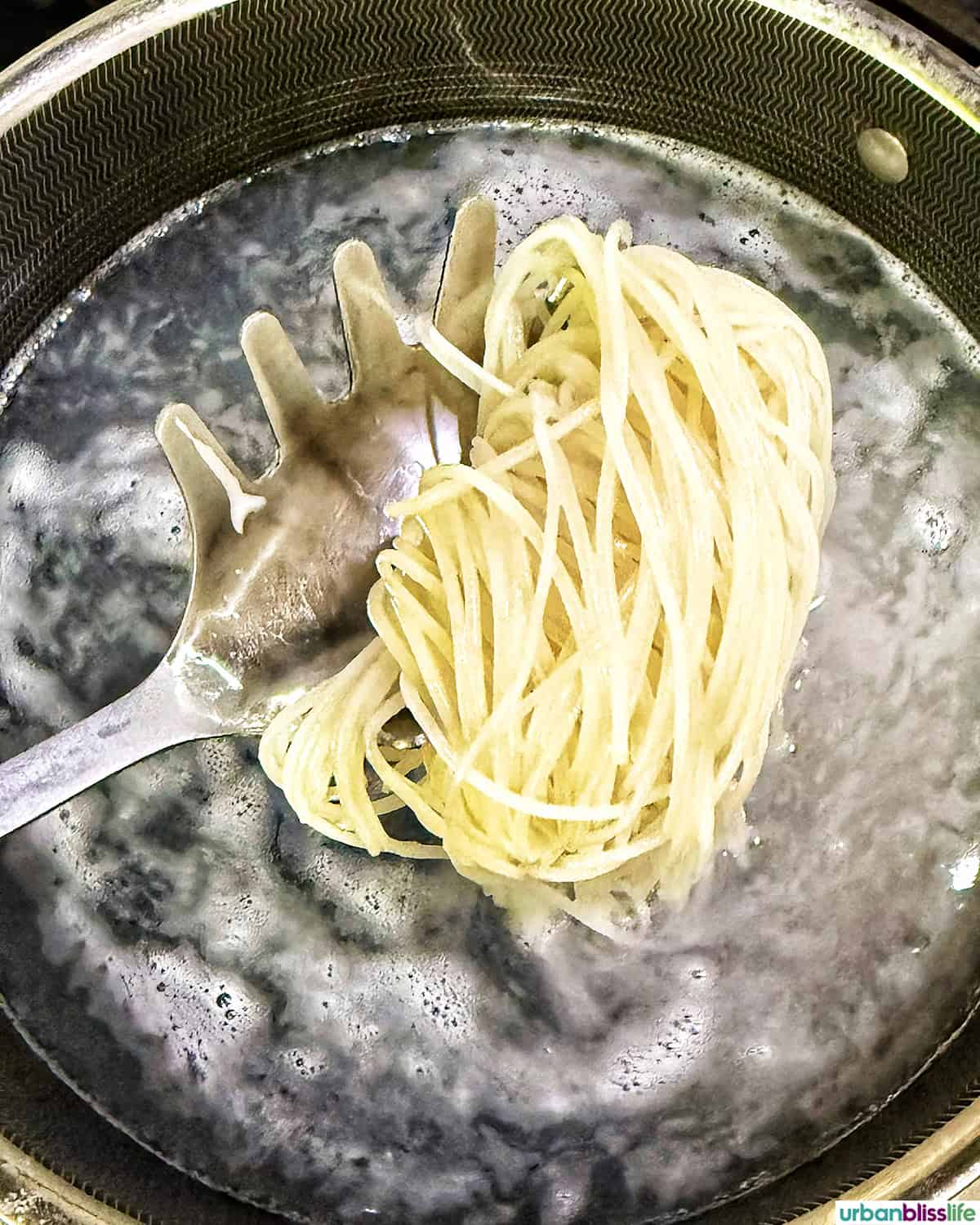 spooning pasta out of a pot of boiling water.