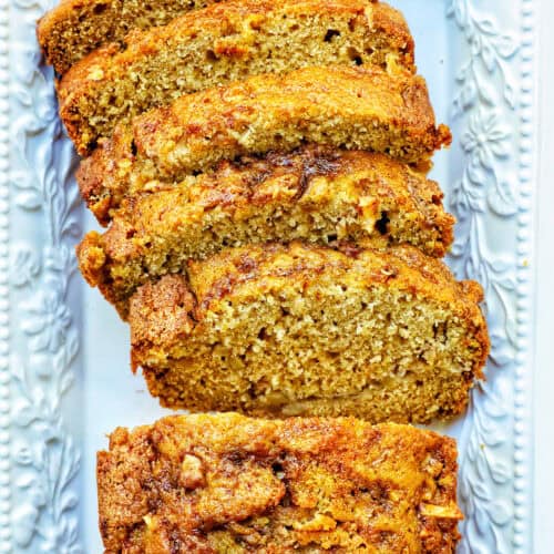 sliced apple cinnamon loaf cake on a white platter.