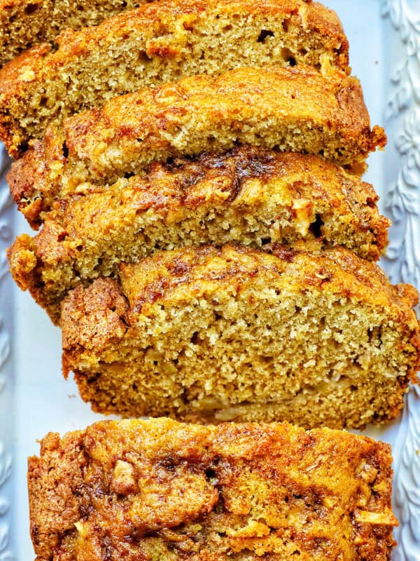 sliced apple cinnamon loaf cake on a white platter.