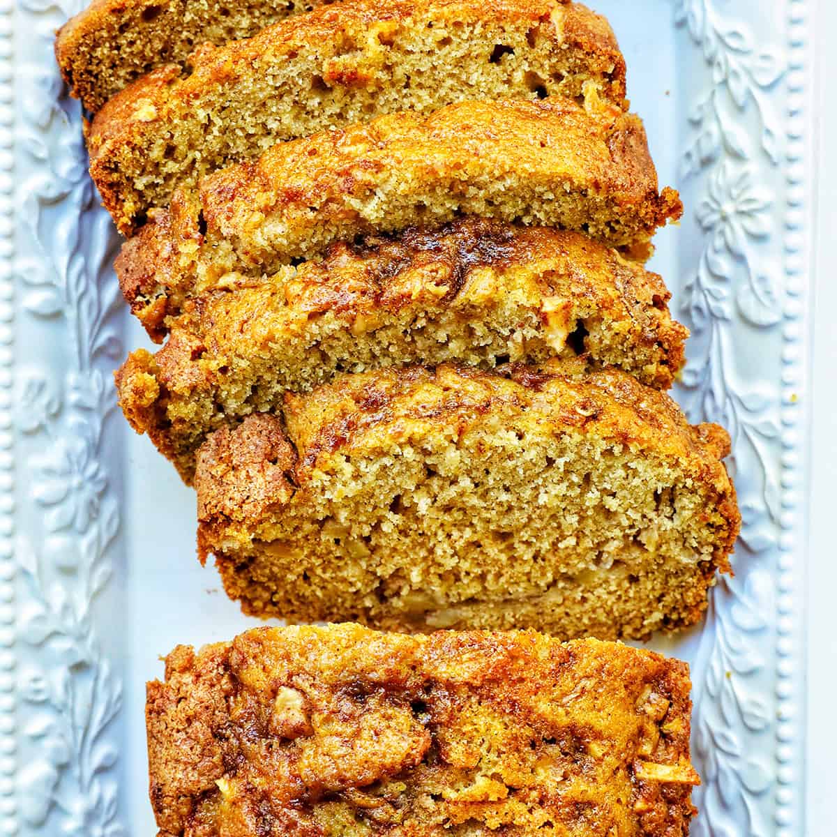 sliced apple cinnamon loaf cake on a white platter.