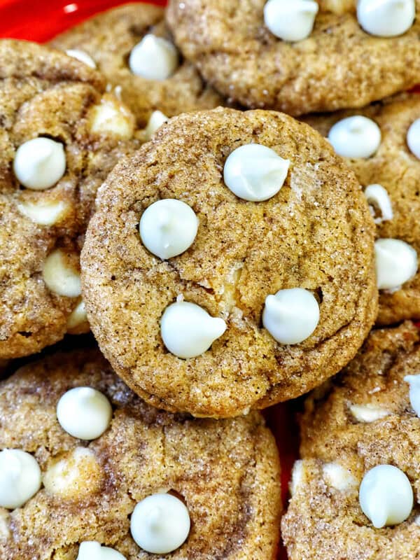 stack of pumpkin white chocolate chip cookies on an orange plate.