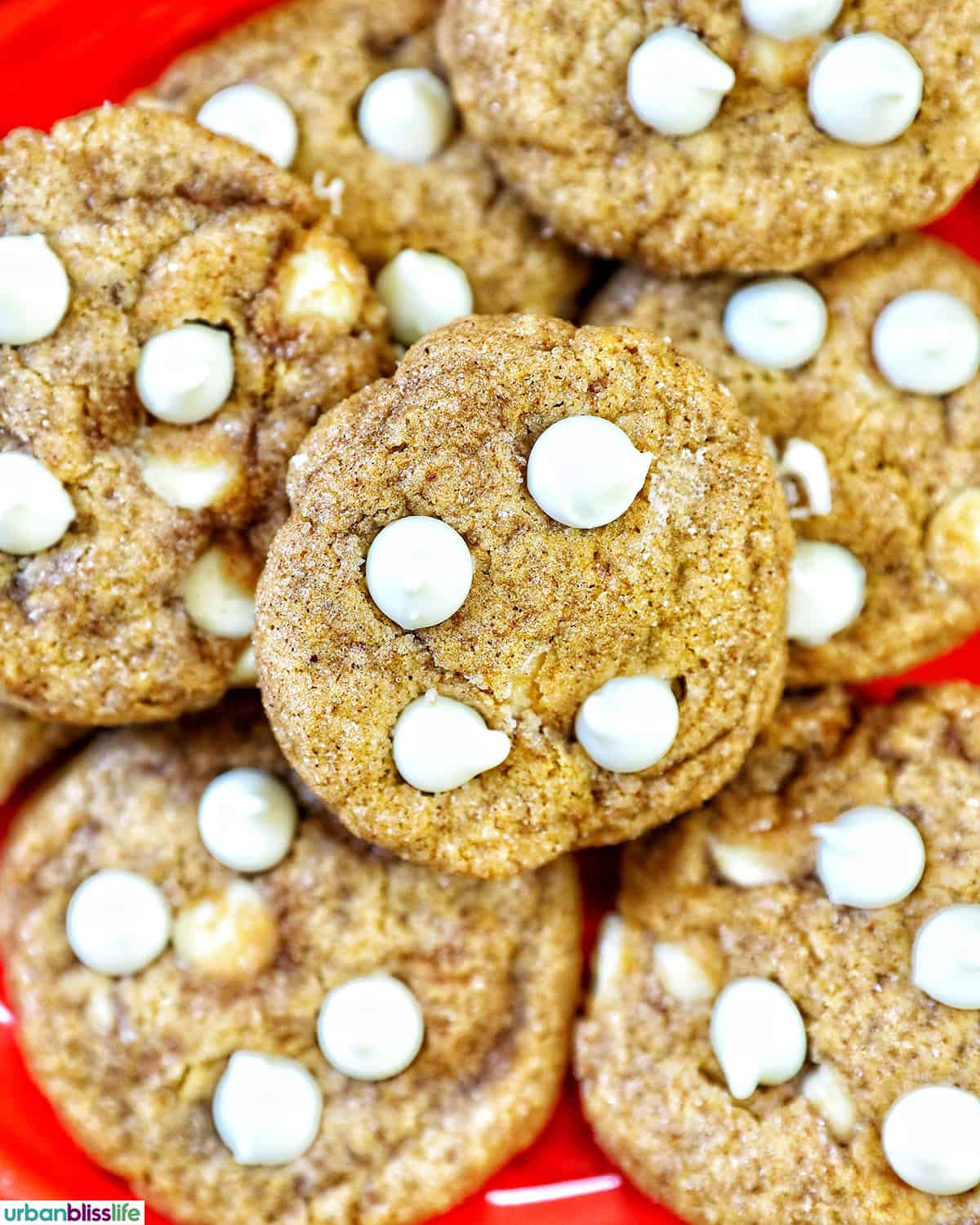 stack of pumpkin white chocolate chip cookies on an orange plate.