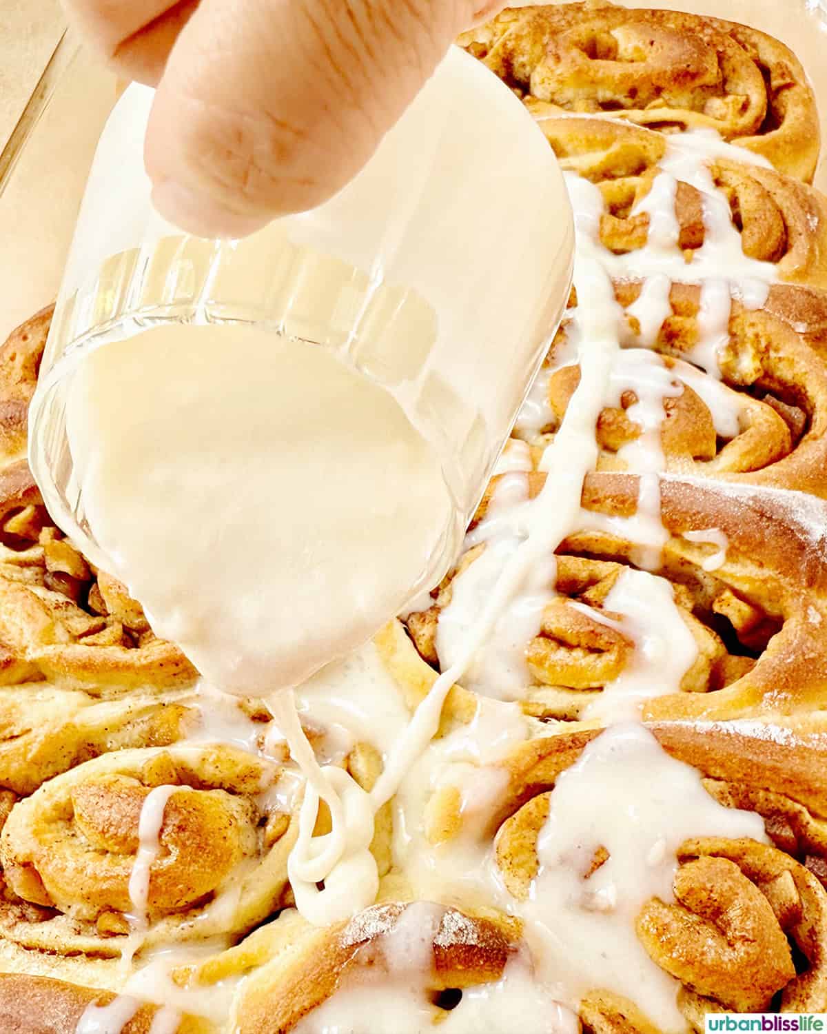pouring icing over the cinnamon rolls. 