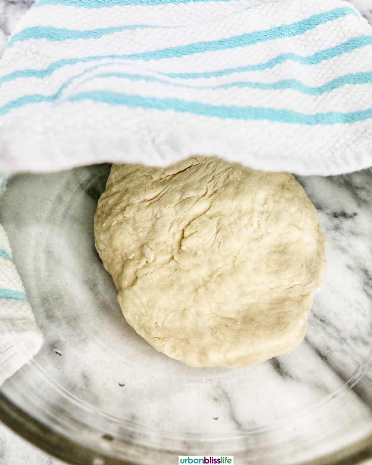 dough in a bowl with a towel about to cover it.