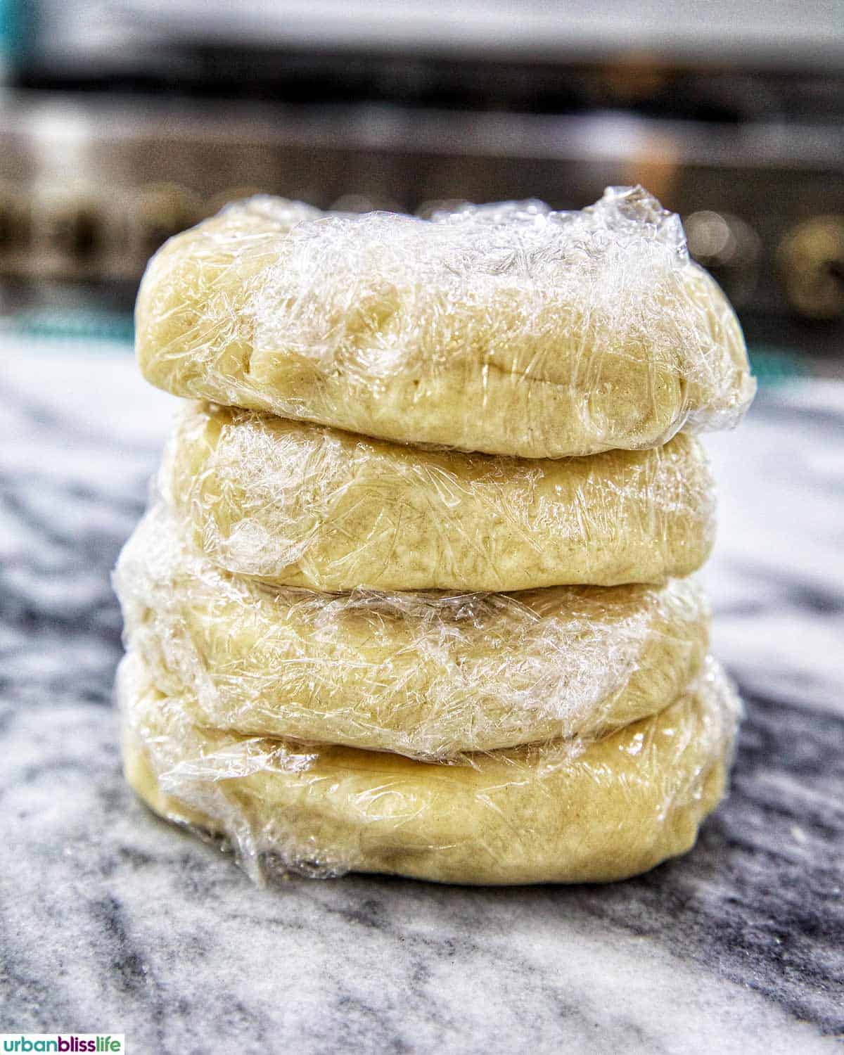 dough wrapped in plastic wrap stacked to chill.