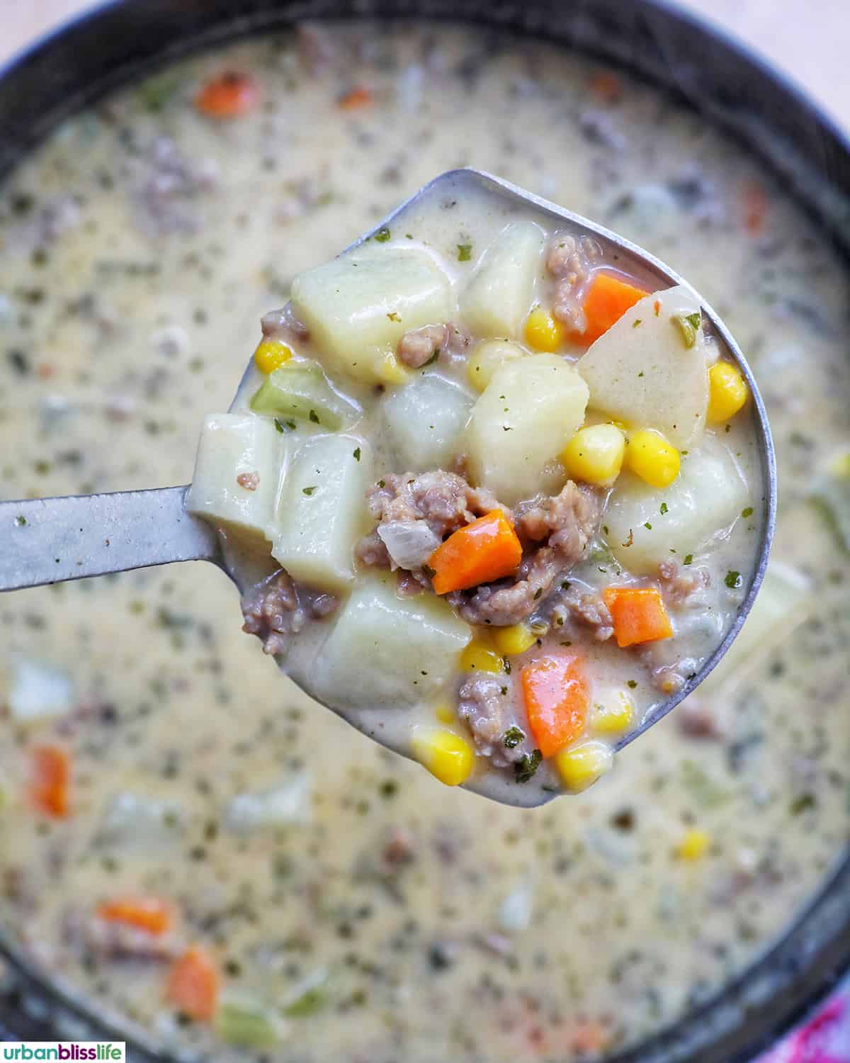 ladle of carrots, celery, garlic, onions cooking in a pot.