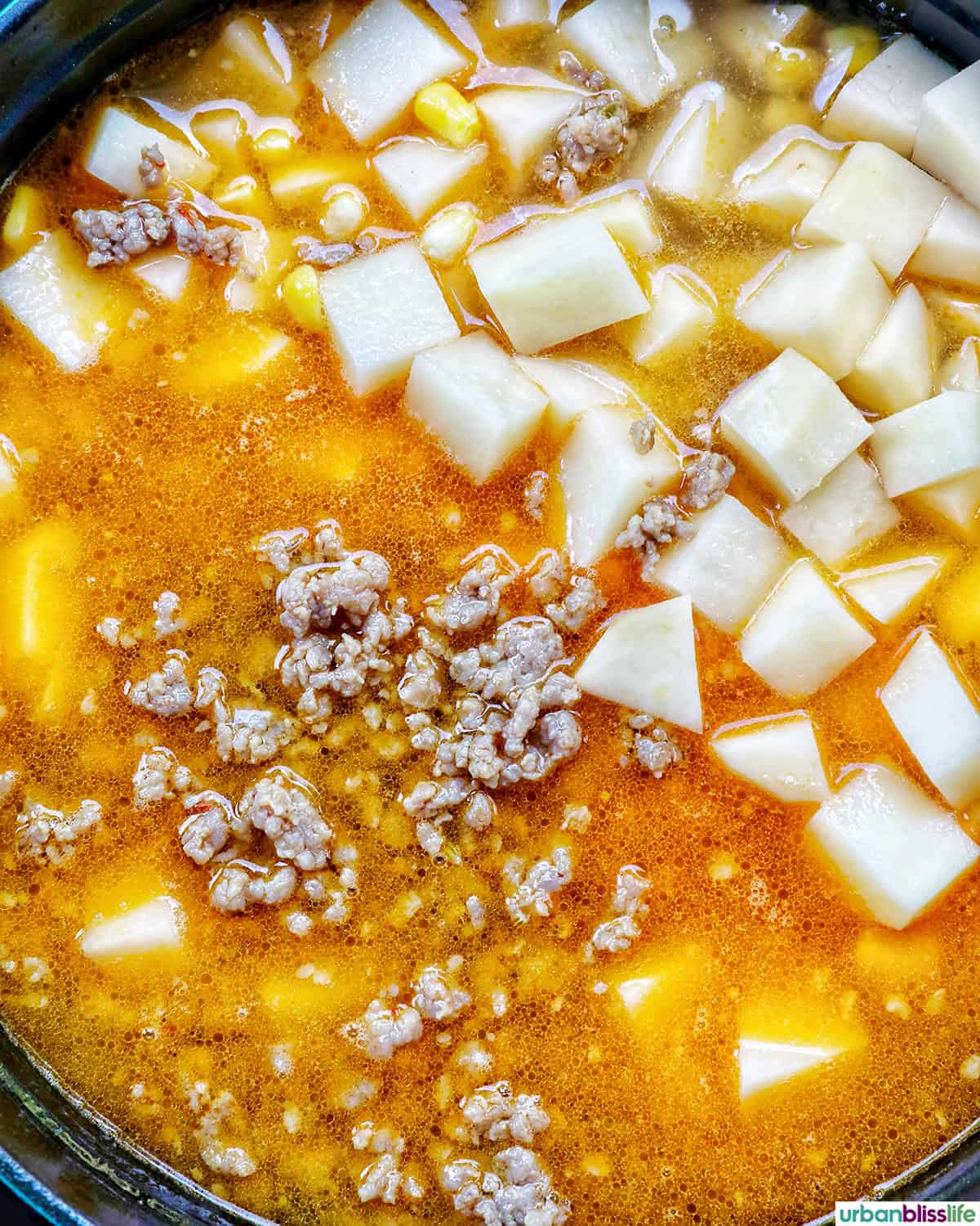 sausage and potatoes added to a pot.