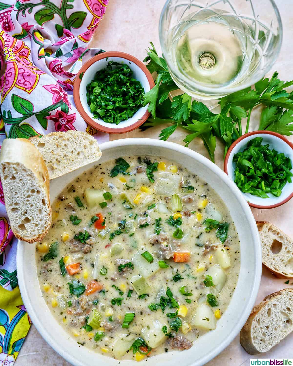 bowl of corn and sausage chowder with glass of white wine.