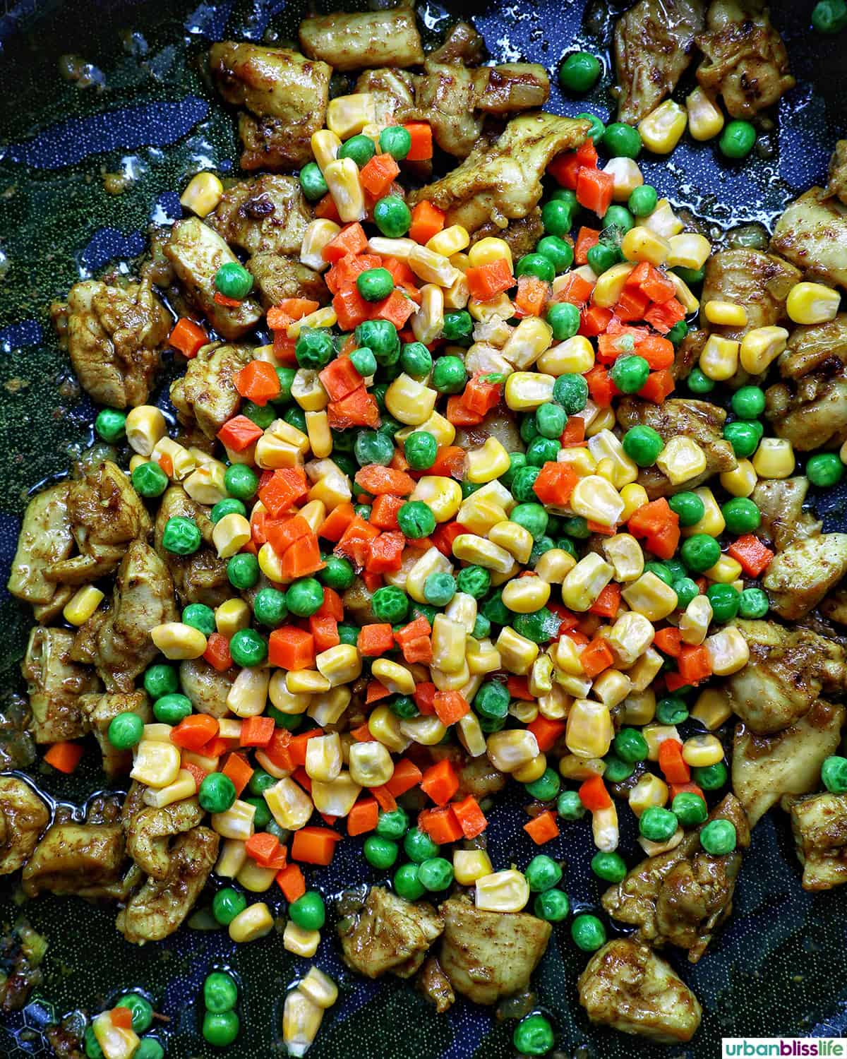 mixed vegetables and chicken cooking in a pan.