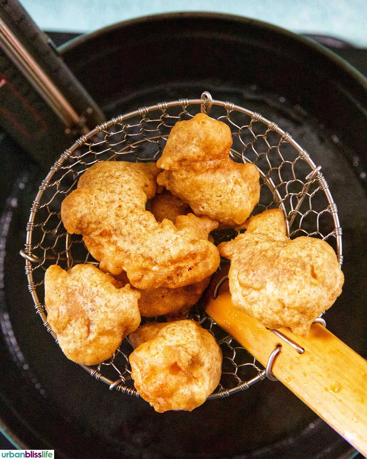 beer battered shrimp in a spider over a dutch oven of hot oil.