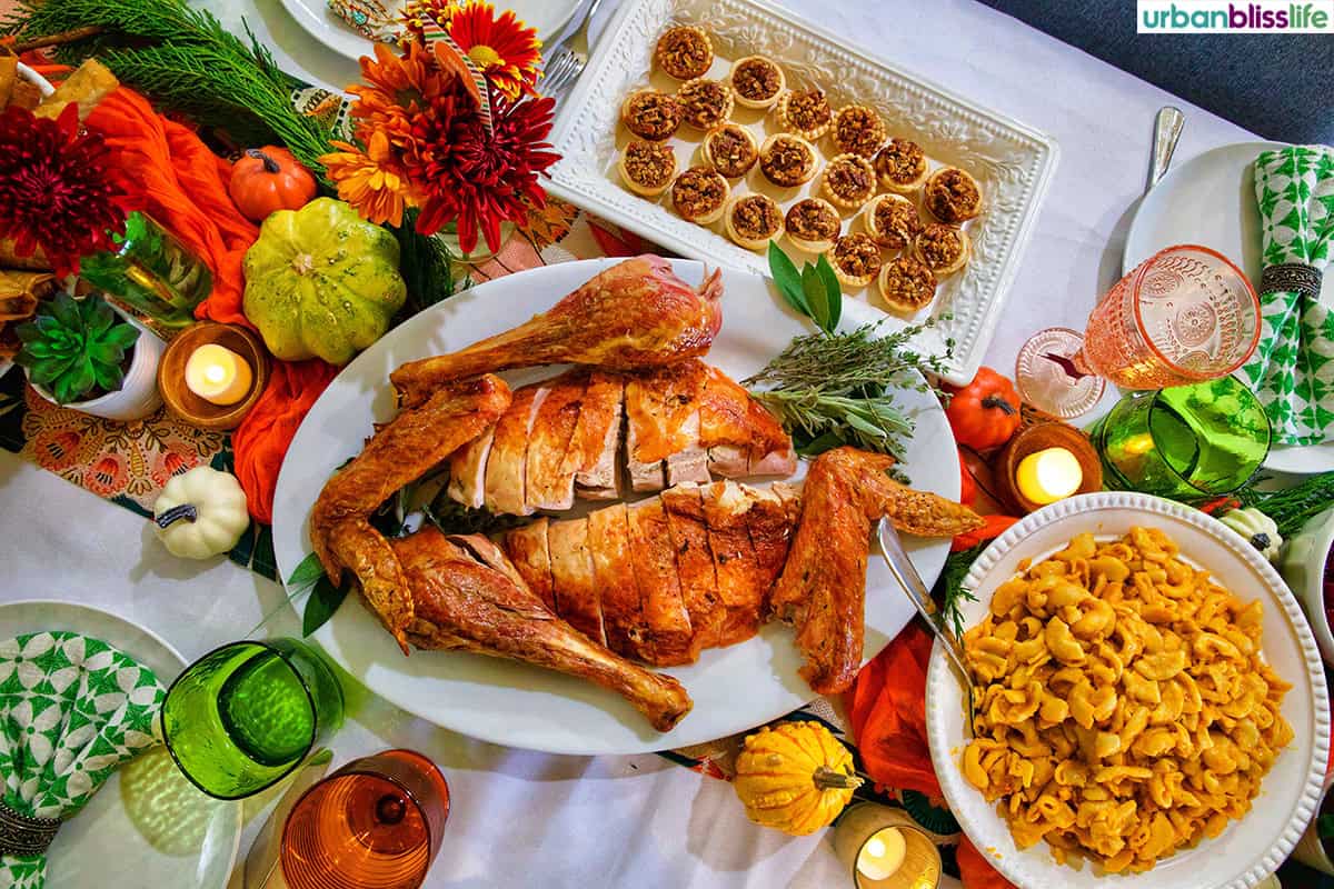 Friendsgiving Thanksgiving turkey on a table with mini pecan pies and butternut squash mac and cheese.