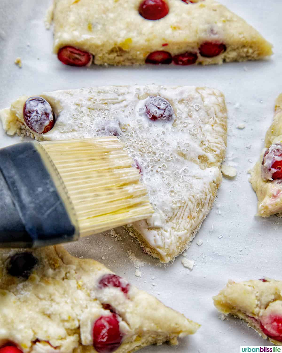 brushing glaze onto orange cranberry scones.
