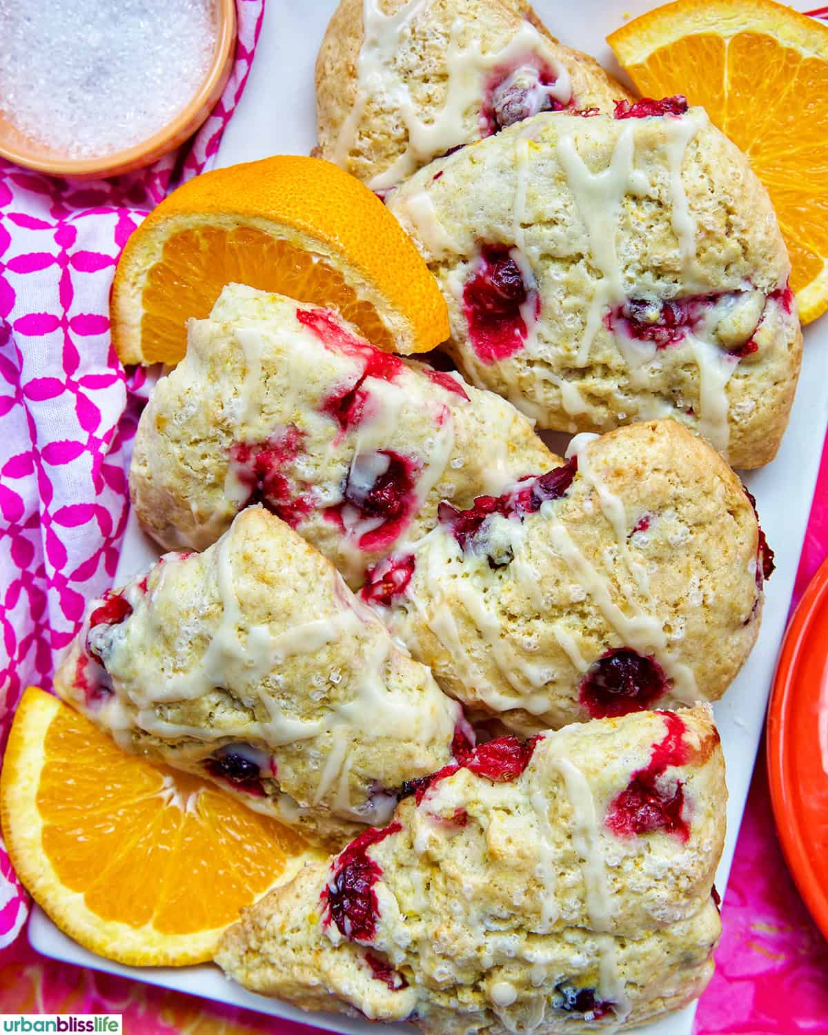 orange cranberry scones with orange slices on a plate.