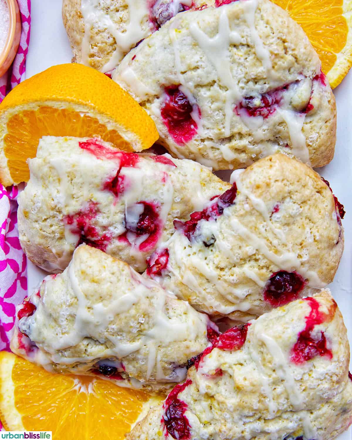 orange cranberry scones with orange slices on a plate.