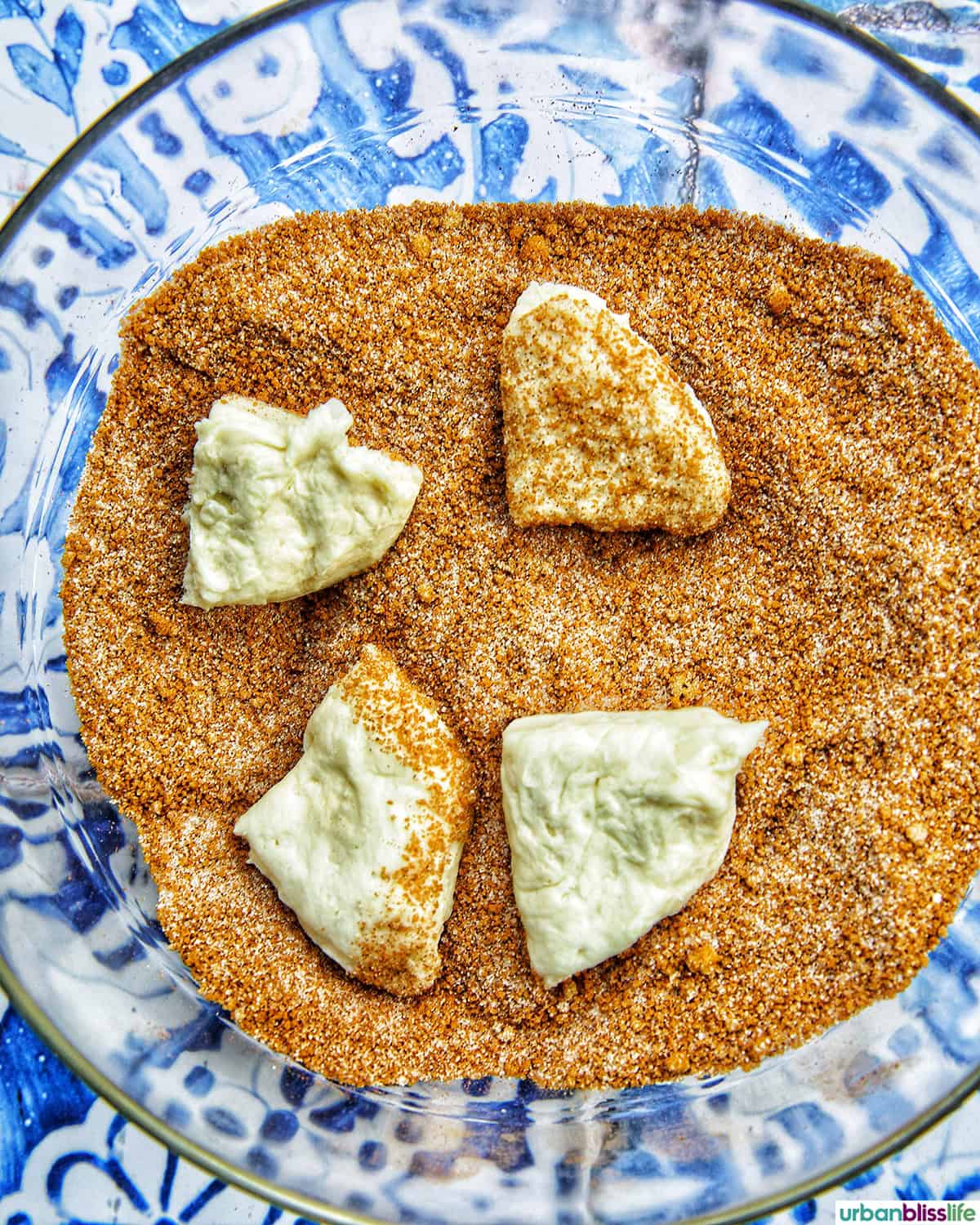 cut biscuit dough in a bowl of cinnamon sugar mixture.